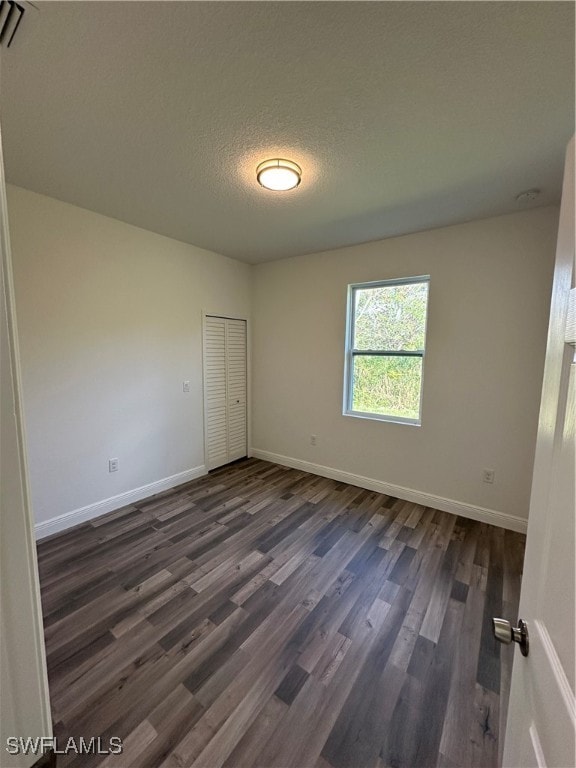 empty room featuring a textured ceiling and dark wood-type flooring