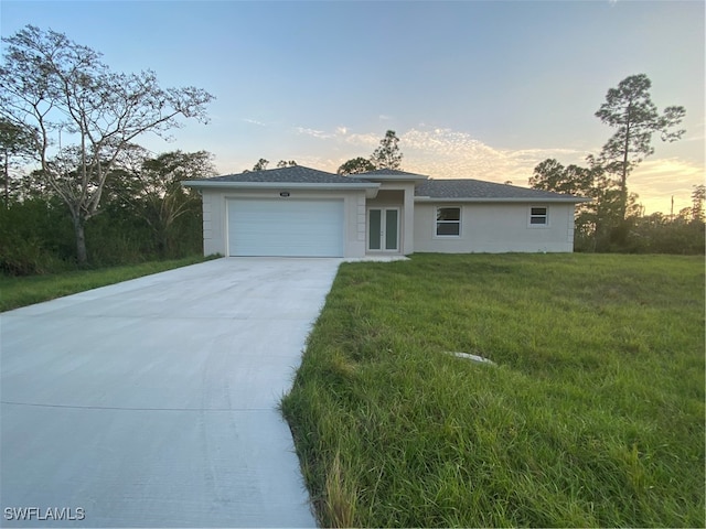 view of front of house with a garage, a yard, and french doors