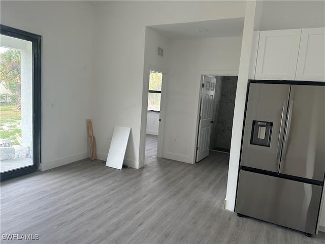 kitchen with white cabinets, stainless steel fridge, and light hardwood / wood-style floors