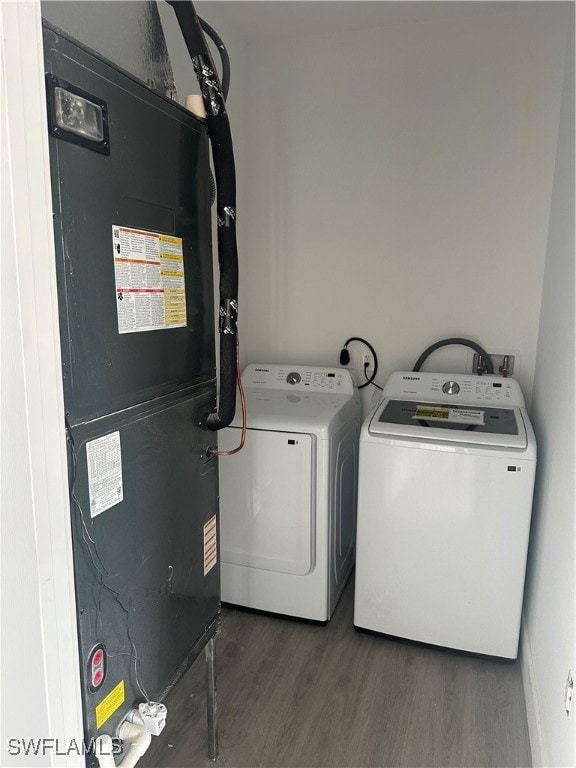 washroom featuring washing machine and dryer, dark wood-type flooring, and heating unit