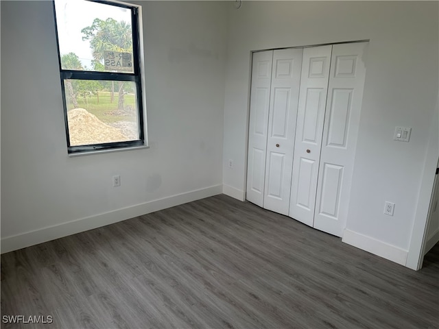 unfurnished bedroom with a closet and dark wood-type flooring