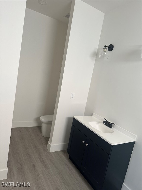 bathroom with toilet, vanity, and hardwood / wood-style flooring