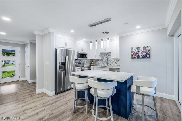 kitchen featuring backsplash, stainless steel appliances, light hardwood / wood-style floors, and decorative light fixtures