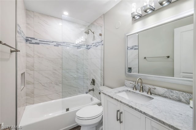 full bathroom featuring vanity, tiled shower / bath combo, and toilet