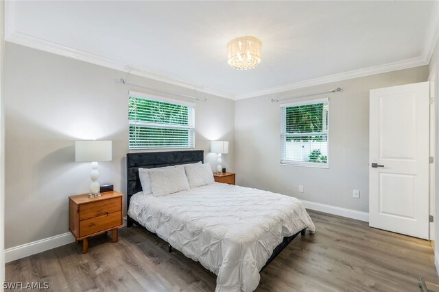 bedroom featuring wood-type flooring, a notable chandelier, and crown molding