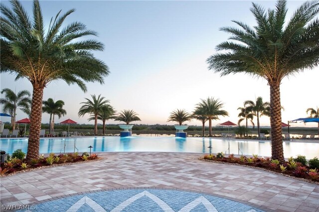 pool at dusk featuring a water view