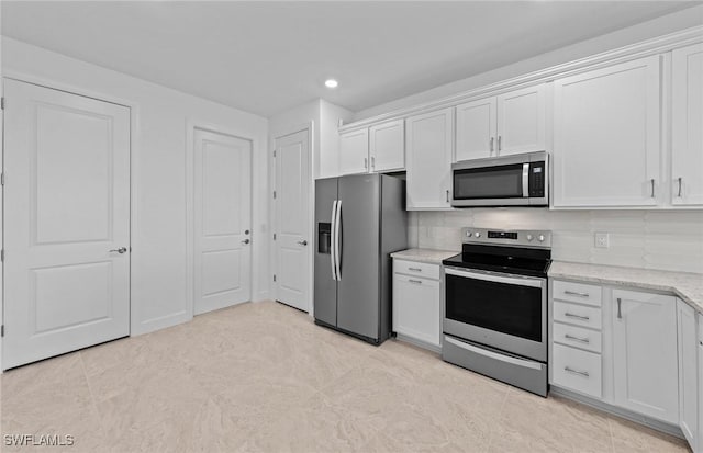 kitchen featuring white cabinetry, stainless steel appliances, light stone counters, and backsplash