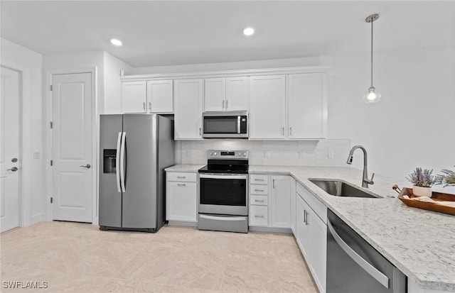 kitchen with appliances with stainless steel finishes, sink, pendant lighting, and white cabinets