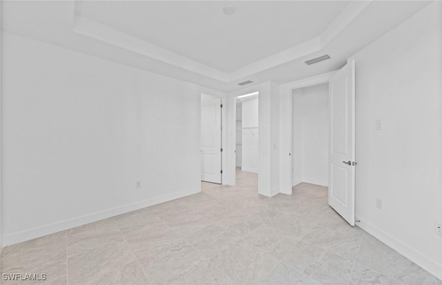 unfurnished bedroom with a walk in closet and a tray ceiling