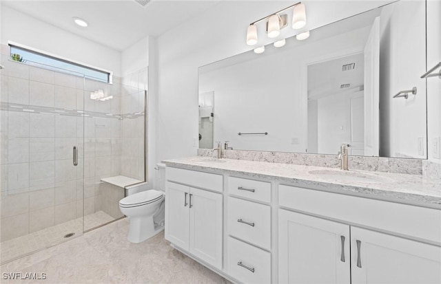 bathroom featuring vanity, a shower with shower door, and toilet