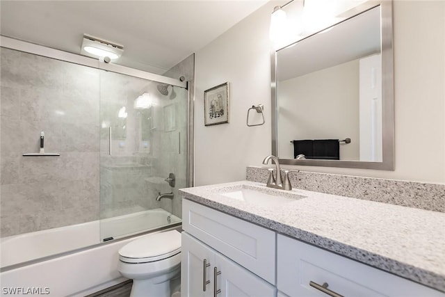 bathroom with enclosed tub / shower combo, toilet, and vanity