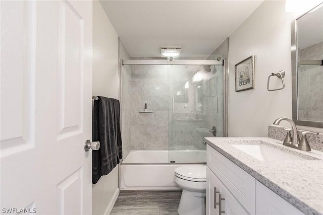 bathroom featuring shower / bath combination with glass door, toilet, wood finished floors, and vanity