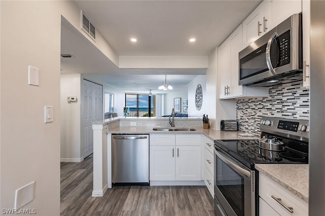 kitchen with visible vents, decorative backsplash, a peninsula, stainless steel appliances, and a sink