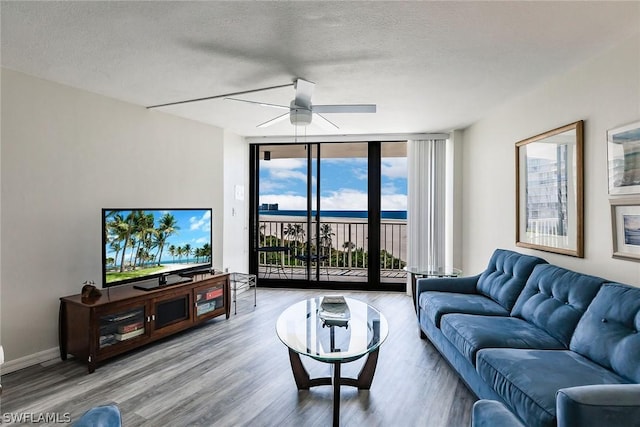 living room with baseboards, a textured ceiling, wood finished floors, and floor to ceiling windows