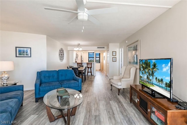 living room with visible vents, baseboards, wood finished floors, and ceiling fan with notable chandelier