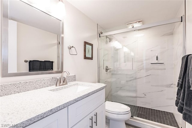 full bath featuring a marble finish shower, toilet, and vanity