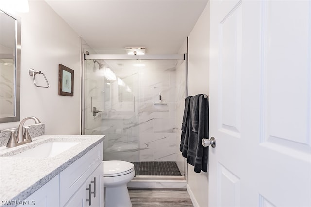 bathroom featuring hardwood / wood-style flooring, a shower with shower door, toilet, and vanity