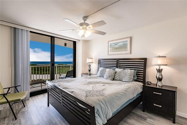 bedroom with light hardwood / wood-style flooring, access to exterior, a water view, a wall of windows, and ceiling fan