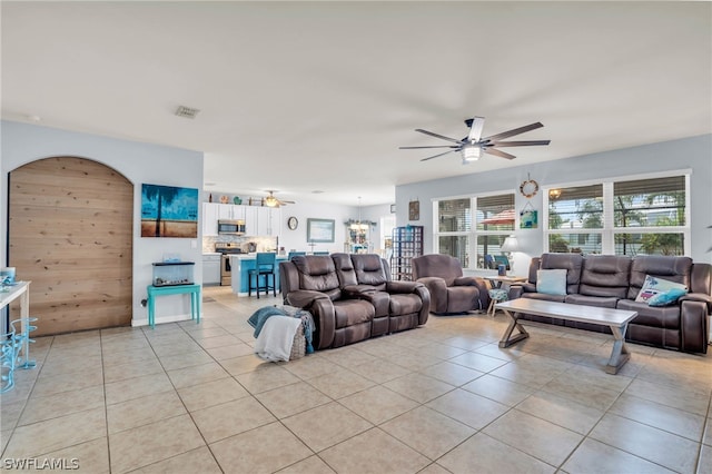 living room with wood walls, light tile patterned floors, and ceiling fan