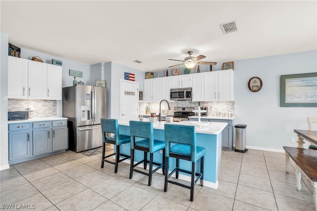 kitchen featuring a breakfast bar area, white cabinets, decorative backsplash, and stainless steel appliances