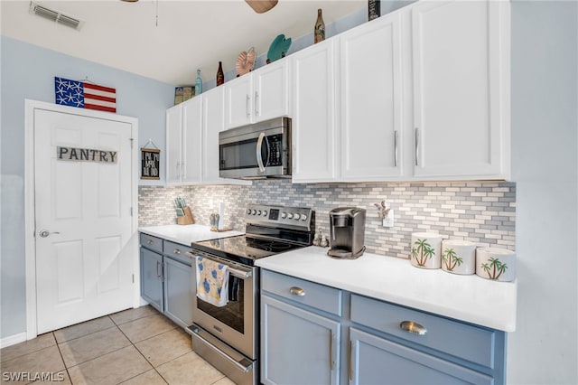 kitchen with ceiling fan, white cabinets, appliances with stainless steel finishes, light tile patterned floors, and backsplash