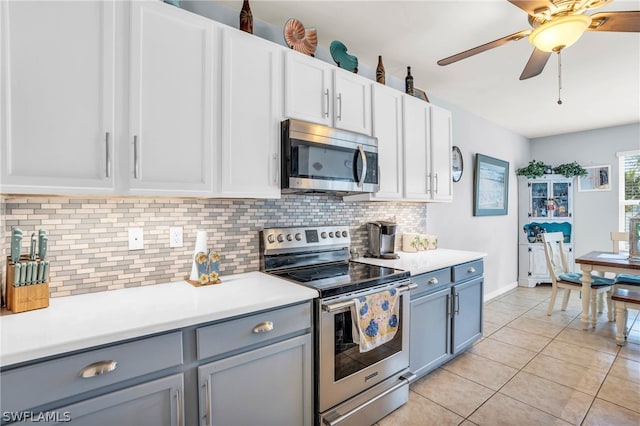 kitchen with gray cabinets, white cabinetry, ceiling fan, stainless steel appliances, and light tile patterned floors