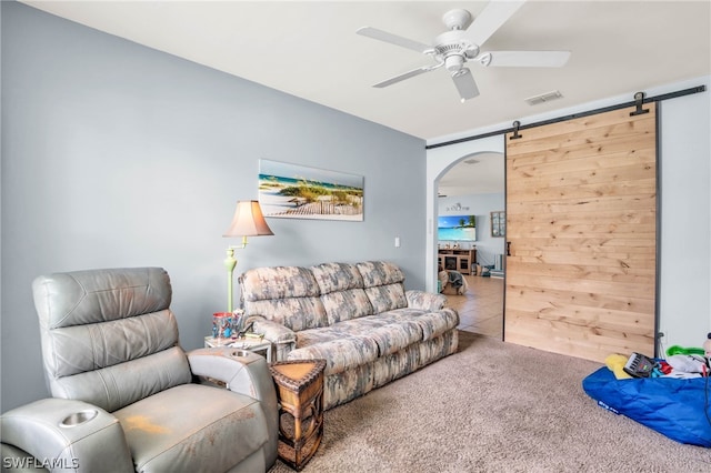 living room featuring light carpet, a barn door, and ceiling fan