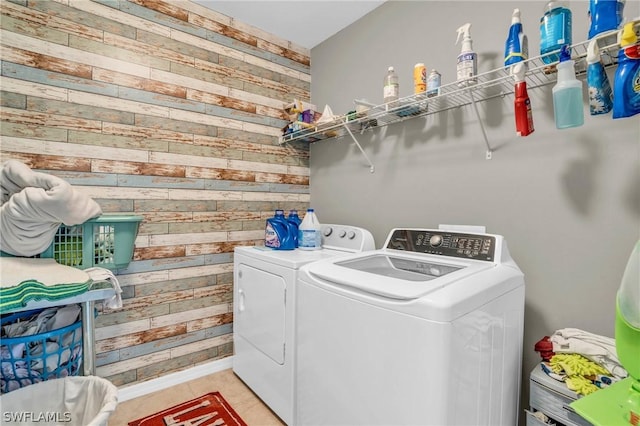 washroom featuring washing machine and clothes dryer and wood walls