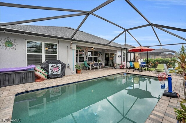 view of swimming pool with a patio, ceiling fan, and glass enclosure