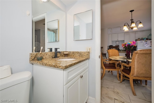 bathroom with tile patterned flooring, toilet, vanity, and an inviting chandelier