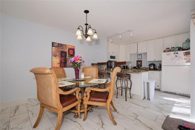 tiled dining space featuring a chandelier and track lighting