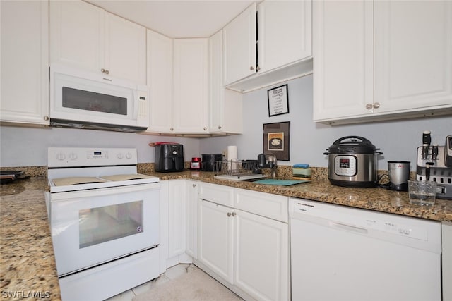 kitchen with dark stone countertops, white cabinetry, white appliances, and light tile patterned floors