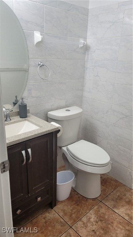 bathroom featuring vanity, toilet, tile patterned flooring, and tile walls