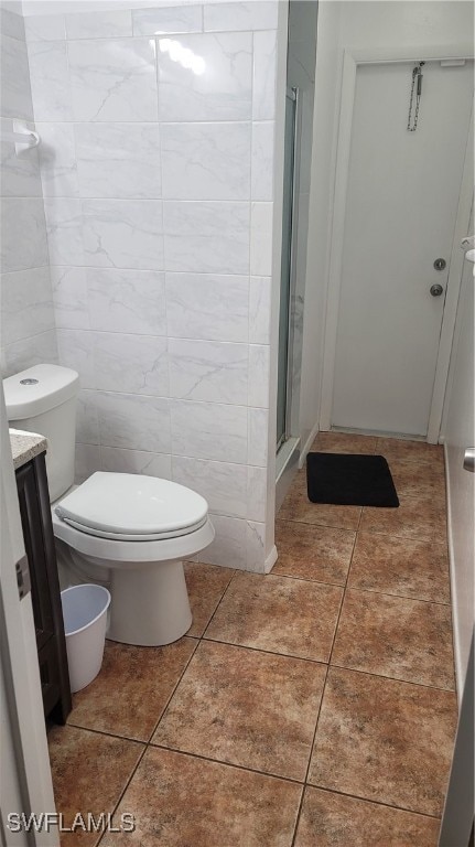 bathroom featuring vanity, tile patterned floors, walk in shower, tile walls, and toilet