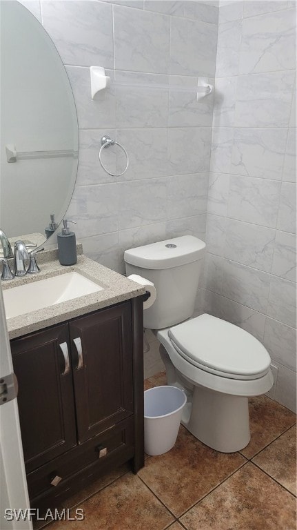 bathroom with tile walls, tile patterned floors, toilet, and vanity