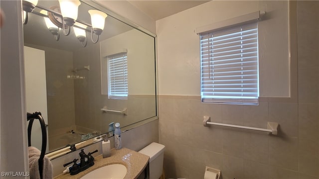 bathroom with toilet, a healthy amount of sunlight, and tile walls