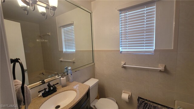 bathroom featuring tile walls, a healthy amount of sunlight, toilet, and vanity