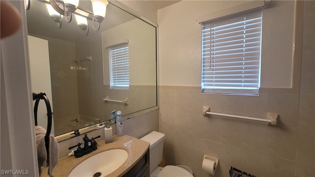 bathroom featuring vanity, tile walls, and toilet