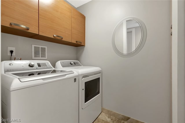 laundry area with washing machine and clothes dryer, cabinets, and light tile patterned flooring