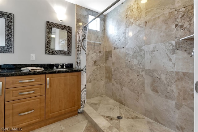 bathroom with vanity, tiled shower, and tile patterned flooring