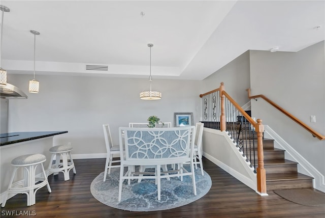 dining room featuring a raised ceiling and dark hardwood / wood-style flooring