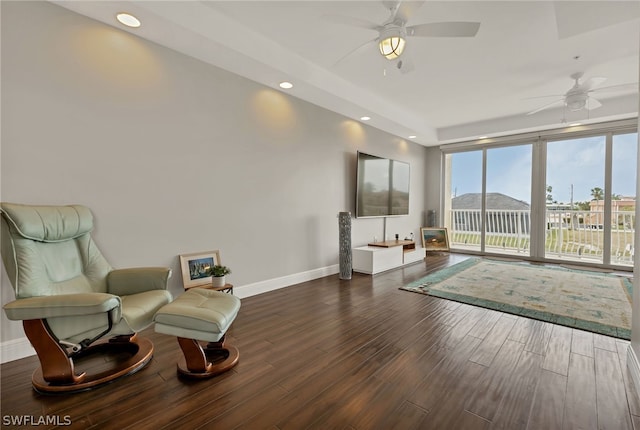 living area featuring ceiling fan and dark hardwood / wood-style flooring