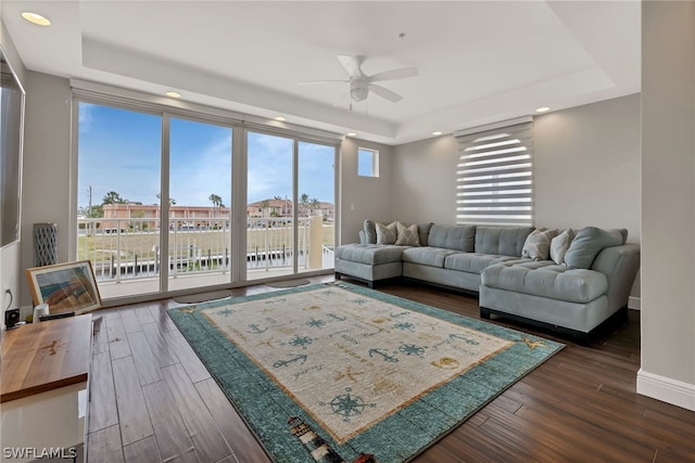 living room with ceiling fan, dark hardwood / wood-style floors, and a tray ceiling