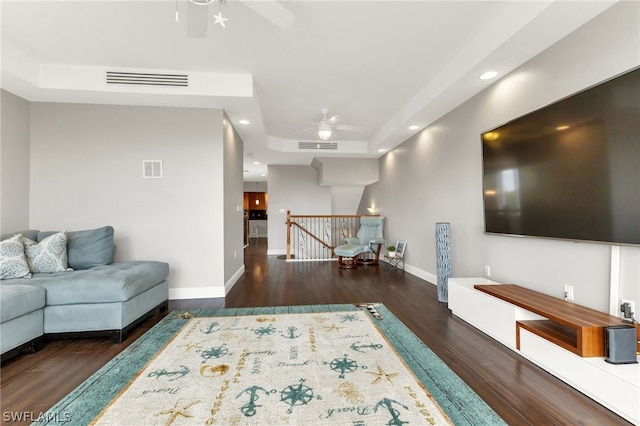 living room featuring a raised ceiling, ceiling fan, and dark hardwood / wood-style floors