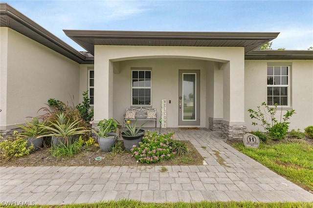 entrance to property with stone siding, covered porch, and stucco siding