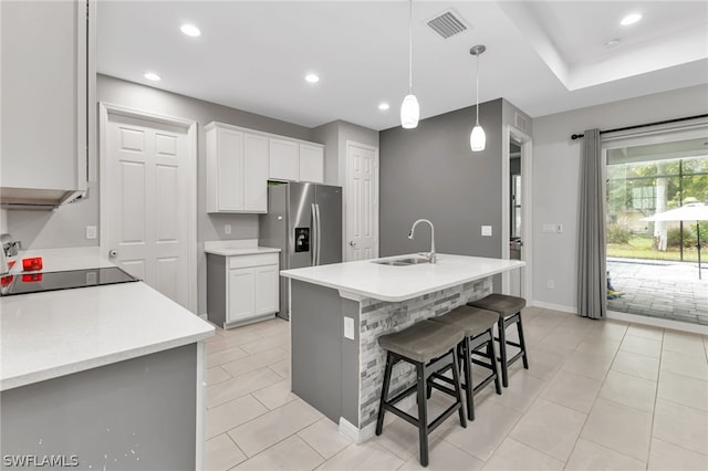 kitchen with white cabinetry, hanging light fixtures, sink, a center island with sink, and light tile patterned floors