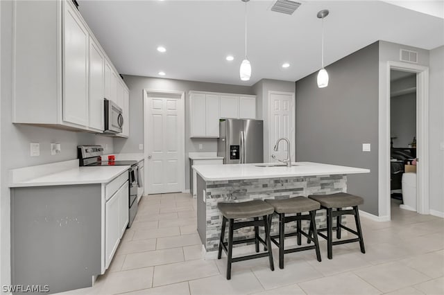 kitchen with a kitchen island with sink, light tile patterned floors, appliances with stainless steel finishes, and sink