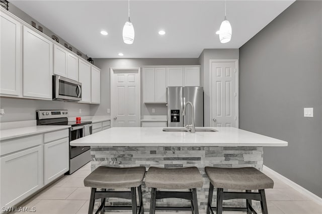 kitchen with appliances with stainless steel finishes, white cabinetry, a center island with sink, and sink