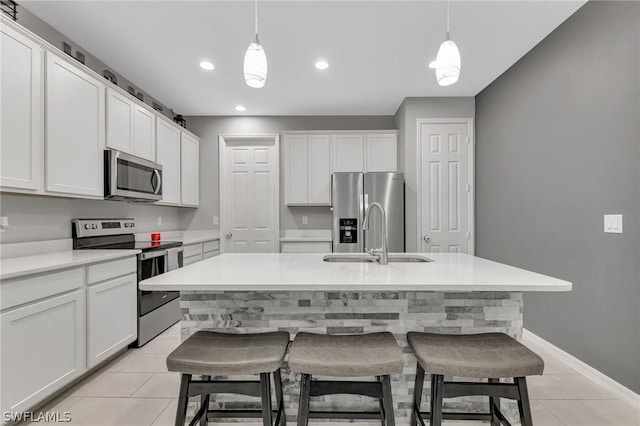 kitchen featuring a breakfast bar area, stainless steel appliances, a sink, and pendant lighting