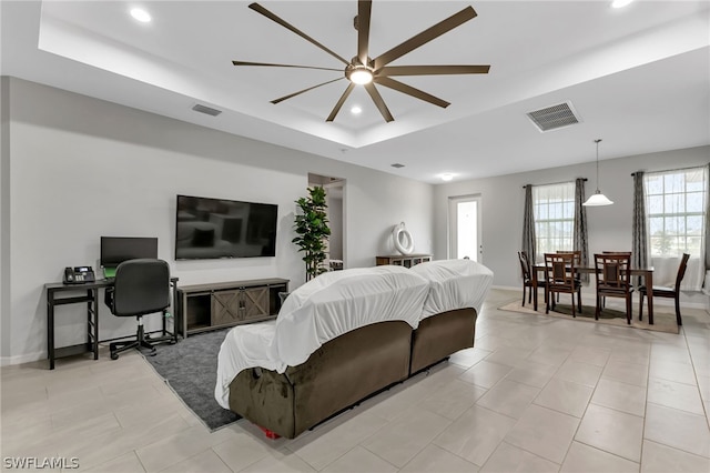 living room featuring light tile patterned flooring, ceiling fan, and a tray ceiling